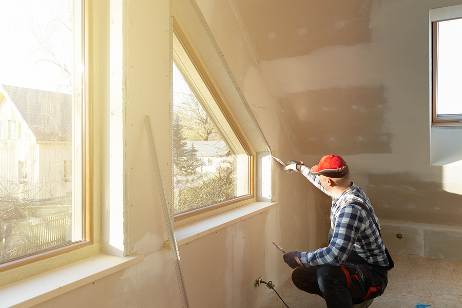 A man finishes installing a window during an attic renovation project.