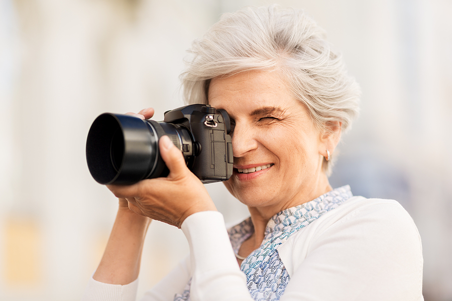 An older woman takes a picture with her digital camera.