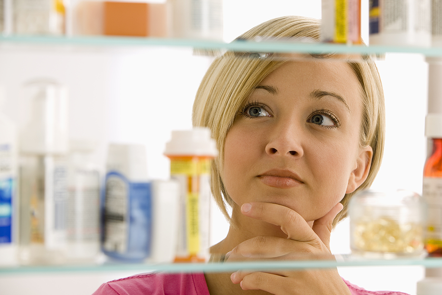 A woman looks in her medicine cabinet for the right medication.