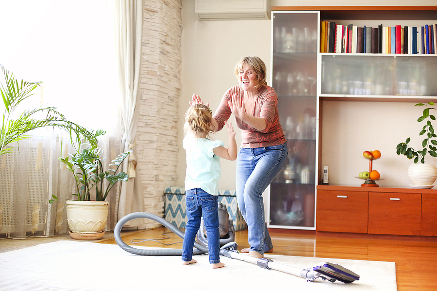 A middle-aged woman gives a high-five to her granddaughter after ridding the house of clutter.